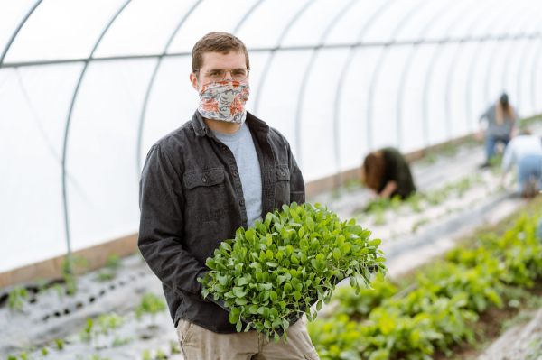 Michael Hinkle holding a tray of plants inside of the greenhouse