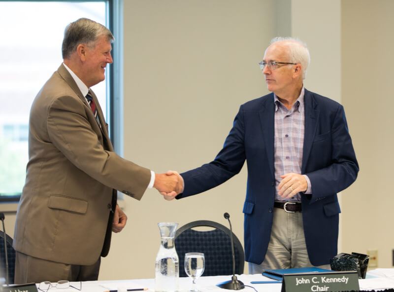 President Thomas J. Haas shakes hands with outgoing board chair John Kennedy.