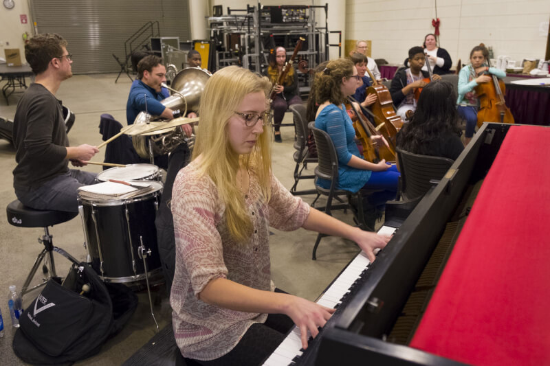 Grand Valley piano performance major Dana Van Dyke playing the piano during a rehearsal.