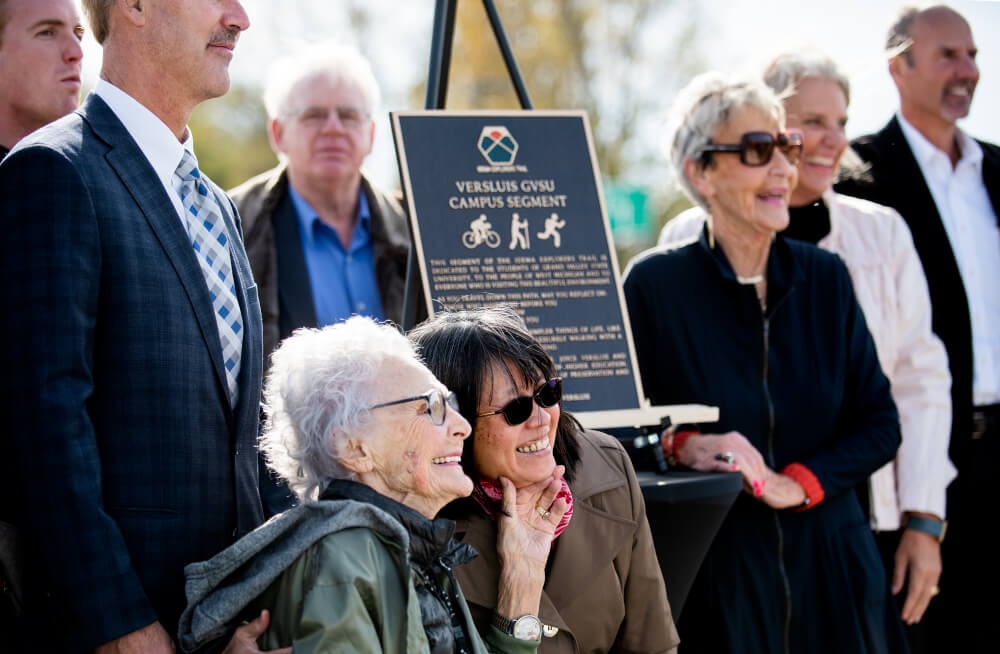 Bea Idema holds the face of her niece, Munyee Aldrink, at a ribbon-cutting ceremony for the Versluis GVSU Campus Segment of the Idema Explorers Trail.