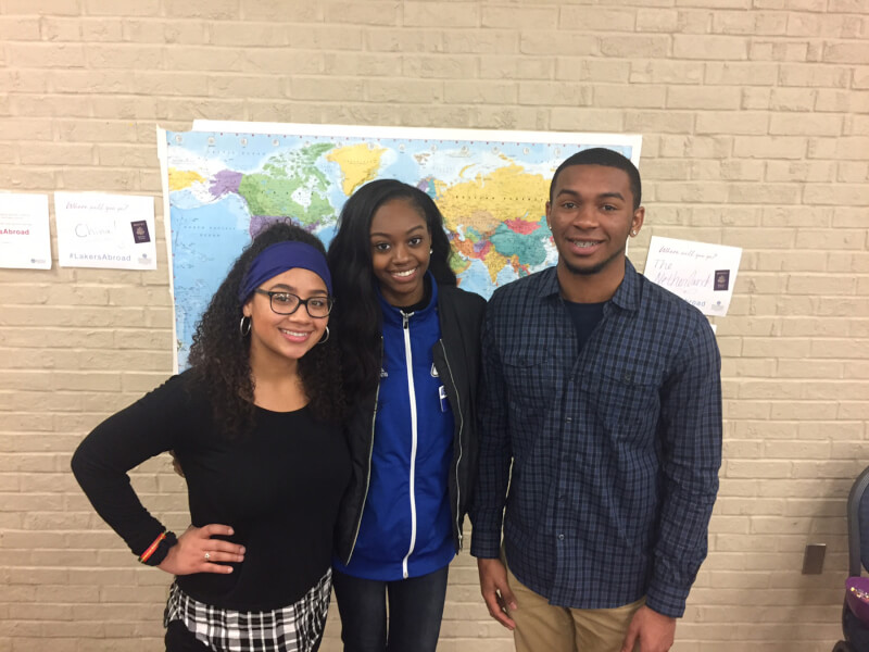 Three people stand in front of a map.