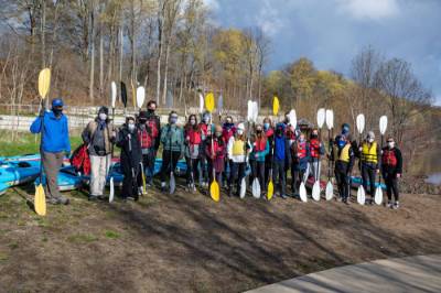 Students and faculty members are pictured holding kayak paddles before an event in the Grand River