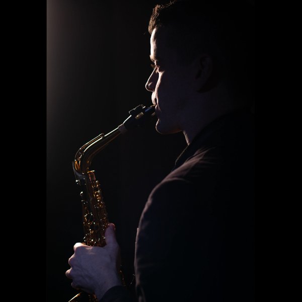 Dan Graser is seen from the side playing the saxophone.