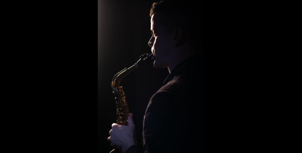 Dan Graser is shown from the side playing saxophone.