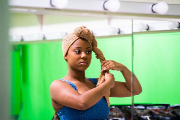 An actor puts on part of her costume.