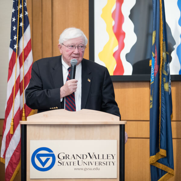 Man speaking behind podium, holding microphone