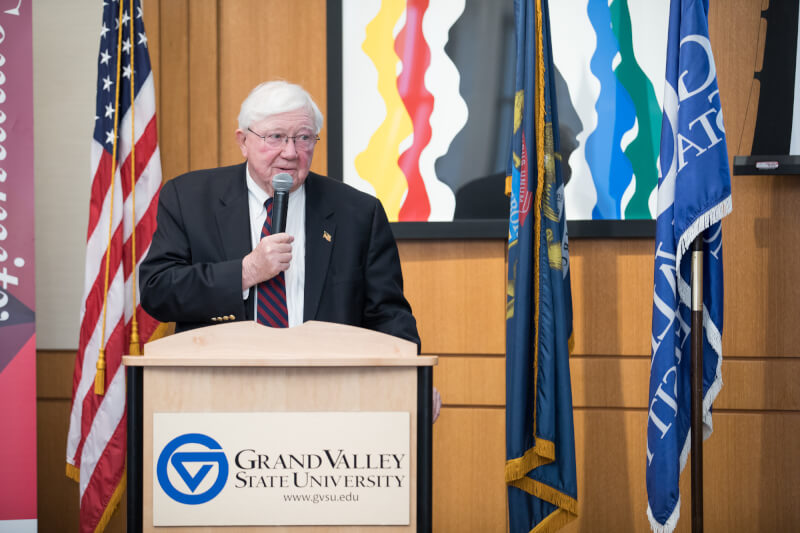 Man speaking behind podium, holding microphone