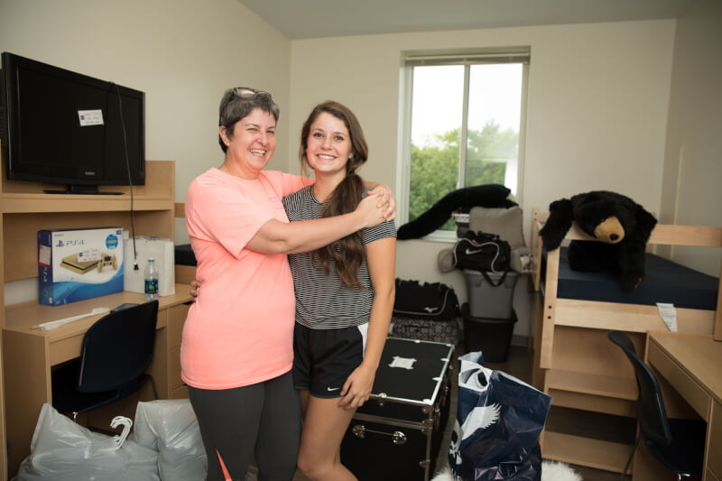  Mother and daughter hugging in a dorm room