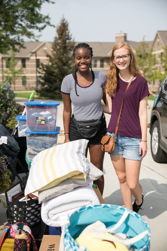  Two female roommate hugging outside of dorm
