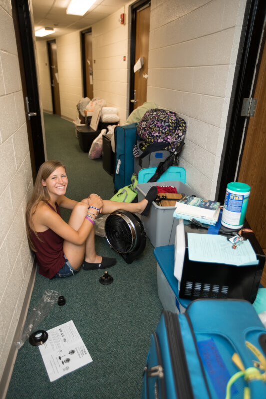 Female student sitting outside of dorm room door