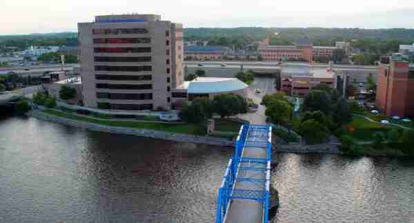A blue bridge spans a river and connects to the campus area.