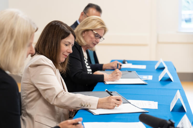 people signing an agreement at a table