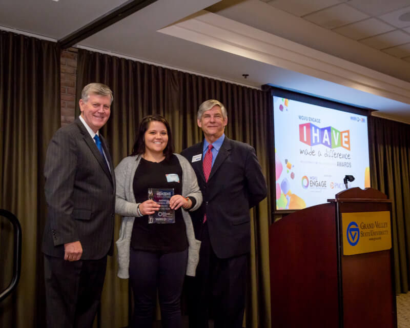Michelle Jokisch-Polo, (center) director of storytelling for Urban Core Collective, won the Person of the Year award. President Thomas J. Haas, left, and WGVU General Manager Michael Walenta, right, presented the award.