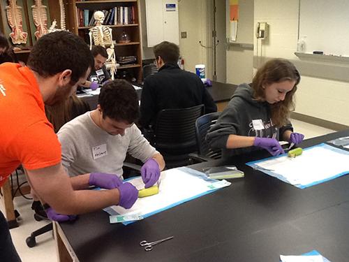 Tim Holloway and Ashley Robinson practice sutures during a clinic led by medical students from the Michigan State University College of Human Medicine.