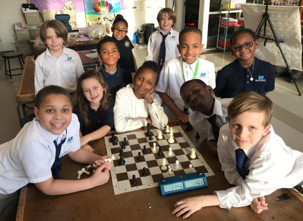 Students pose around chessboard