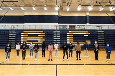group of student socially distant with masks on, standing in high school gym
