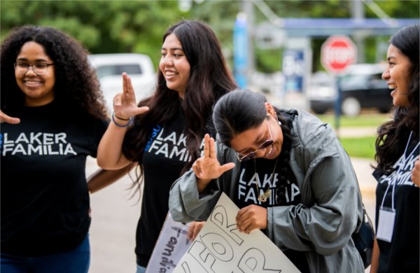 A group of students with Laker Familia, from left, Arianna Westbrooks, Luz Martinez, Lesley Mendez-Velasquez and Lucero Orduna-Rivera laugh together as they welcome students with posters and Anchor Up hand signs during the first day of Valley Campus move-in.  