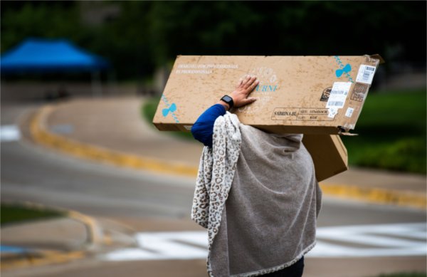 A student carries some furnishings into her room.