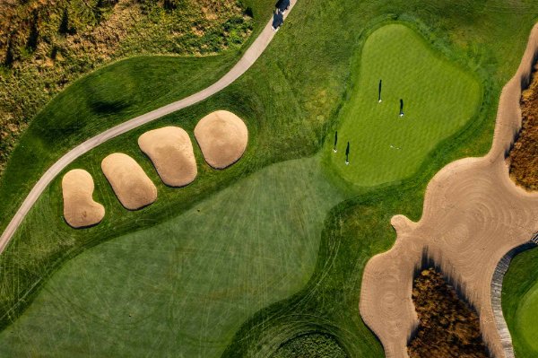  A birds eye view of a golf course and four golfers on the green.