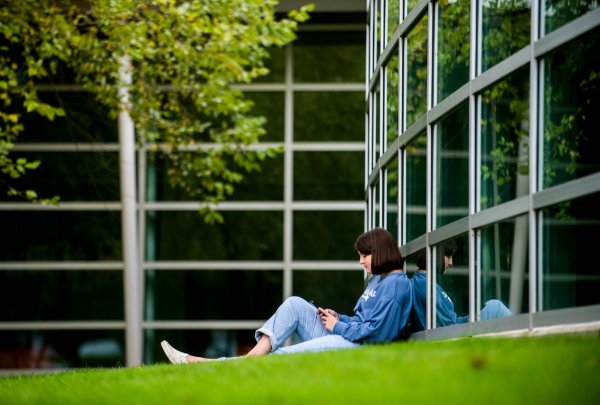  A person sitting against a wall of windows reading a book.