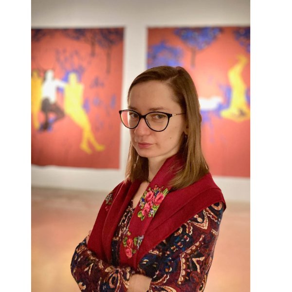 portrait of Iryna Bilan in an art gallery, two works of colorful art behind her
