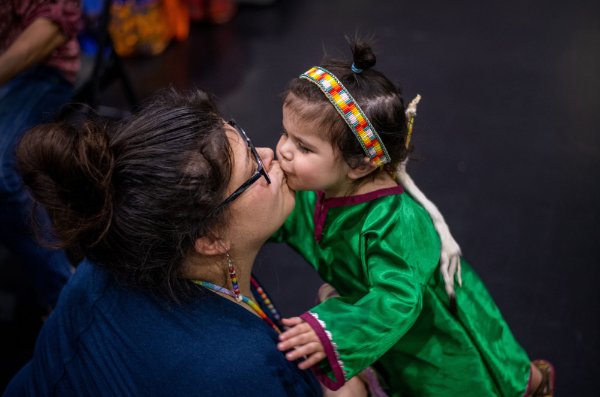 Elise McGowan, left, kisses her daughter Josie McGowan, 2, after getting her ready to dance in the Pow wow.