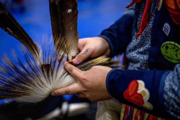 Waasmowin Rinehart works on attaching eagle feathers to the roach of his regalia.