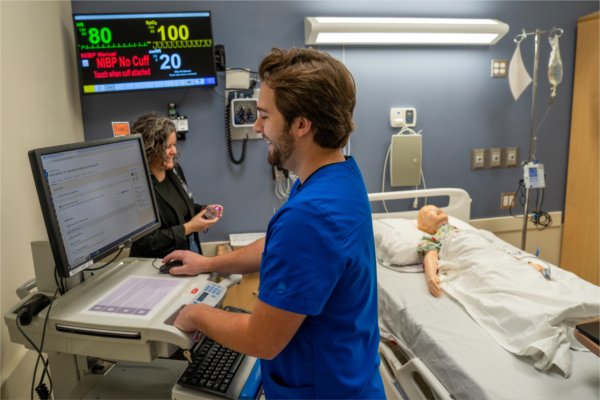 A student checks the settings on a computer before running a simulation in the Interprofessional Simulation Center.