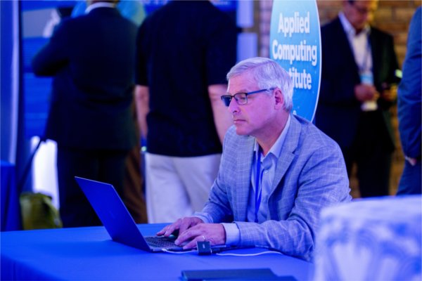 Director of GVSU's Applied Computing Institute Jonathan Engelsma works on a laptop during GVSU's "The Blue Dot Experience," event as part of Tech Week GR in 2024..