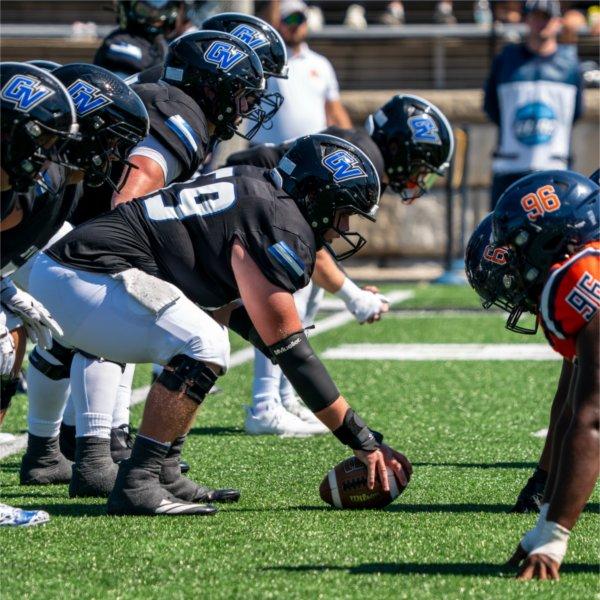 Football lineman line up against each other across the line of scrimmage.