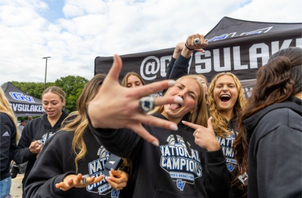 A group of women's basketball players show off their championship rings. 