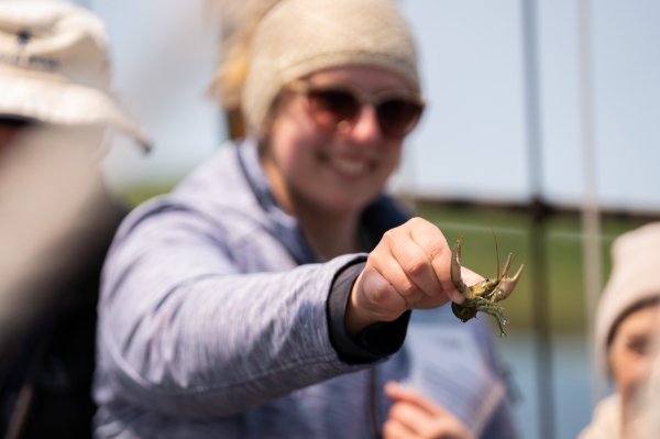 A student holds a crayfish, some species of crayfish are invasive to the waters in northern Michigan.