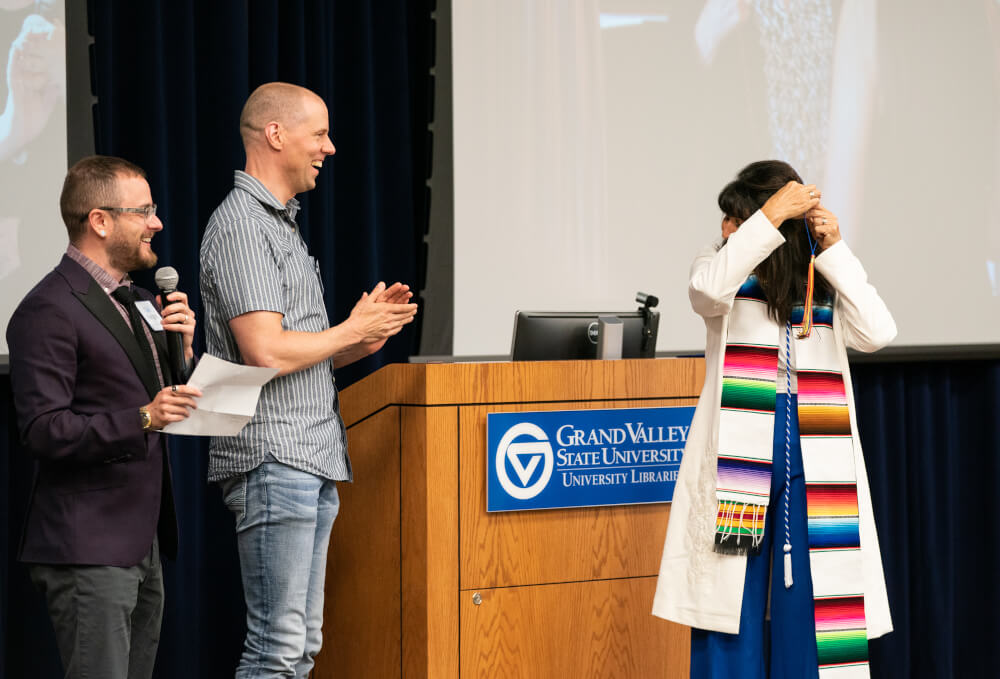 Cael Keegan and Kyle Felker with the LGBT Faculty and Staff Association present President Mantella with a rainbow tassel.