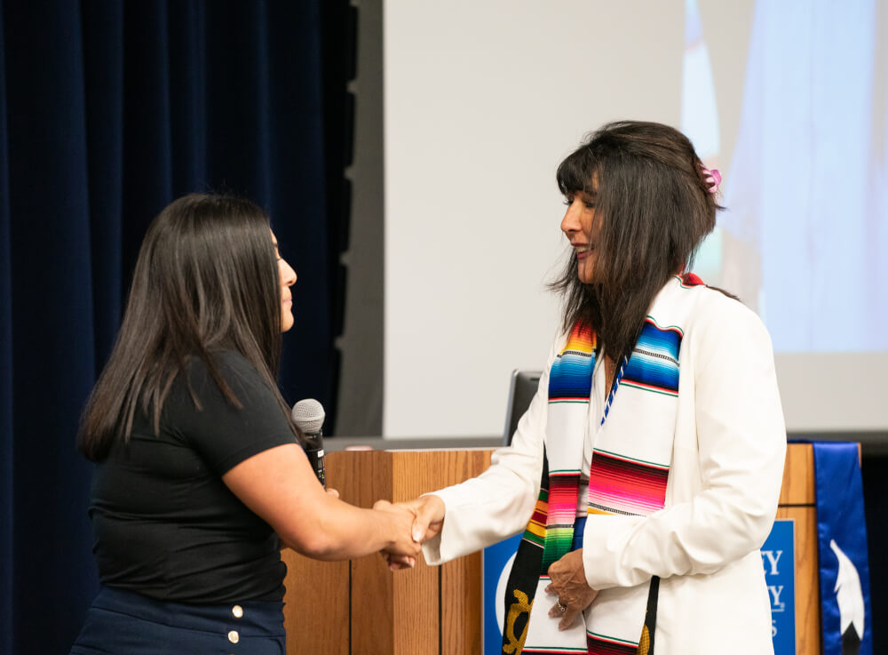 Adriana Almanza with the Latino/a Faculty and Staff Association presents President Mantella with a sarape stole.