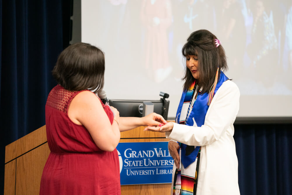 Andrea Riley-Mukavetz with the Native American Advisory Council presents President Mantella with a stole.