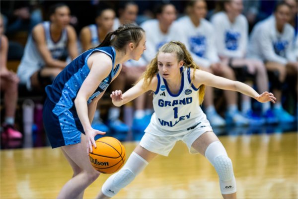 A Grand Valley basketball player reaches for a steal while a Northwood player guards the basketball. 