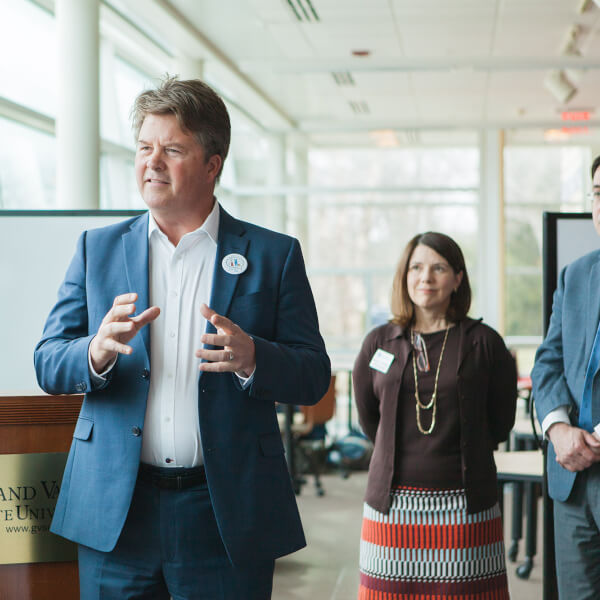 man standing and speaking before crowd