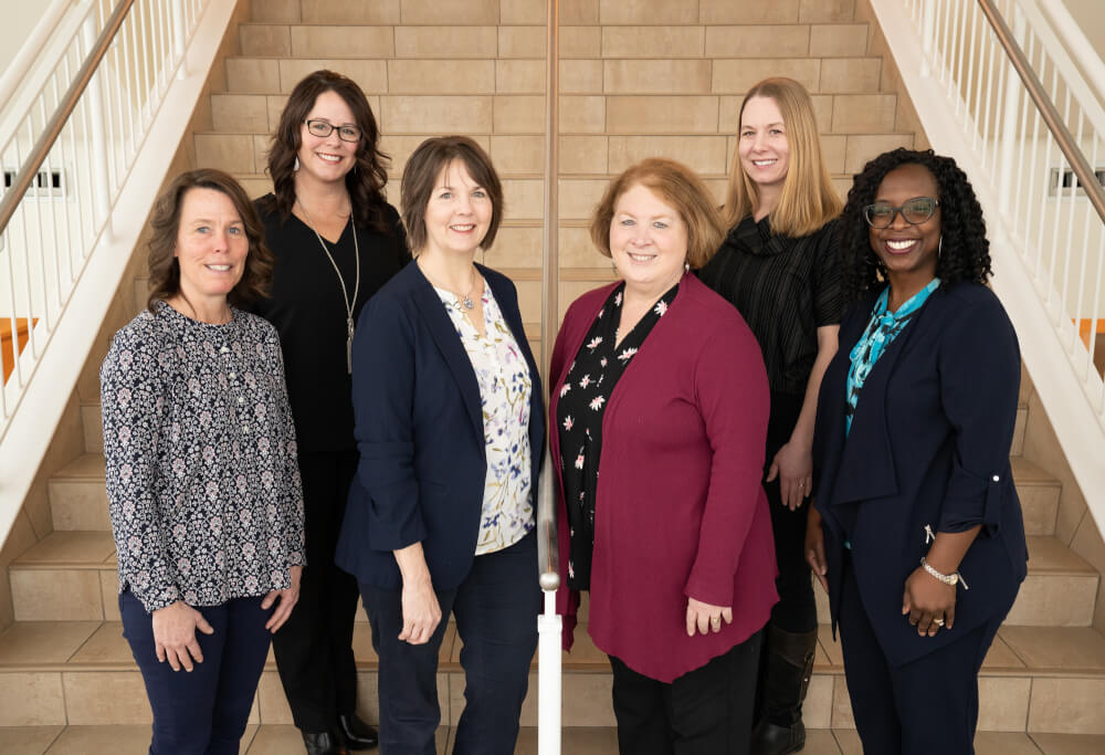 six women in two rows on stairs