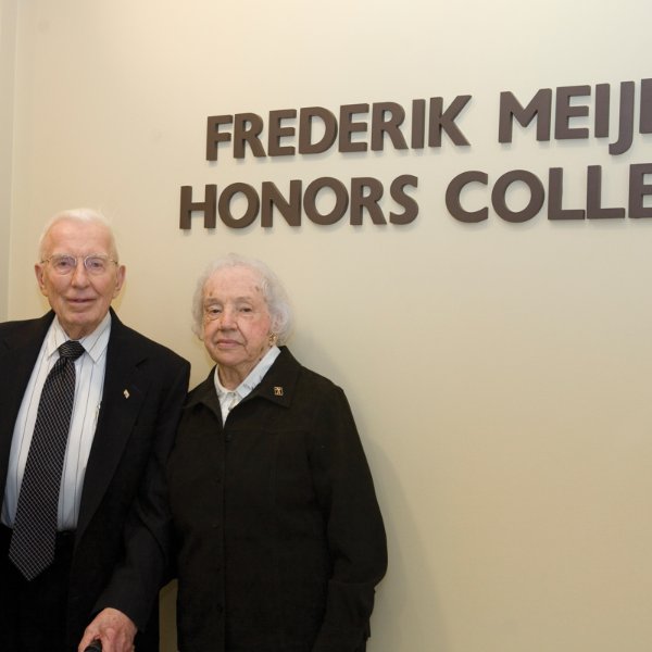 Fred and Lena Meijer in front of a wall with a sign, Frederik Meijer Honors College