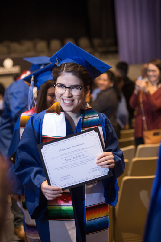 student in cap and gown walking up aisle