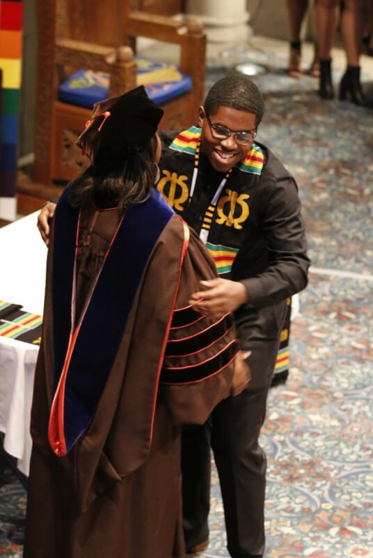 man in cap and gown hugging woman