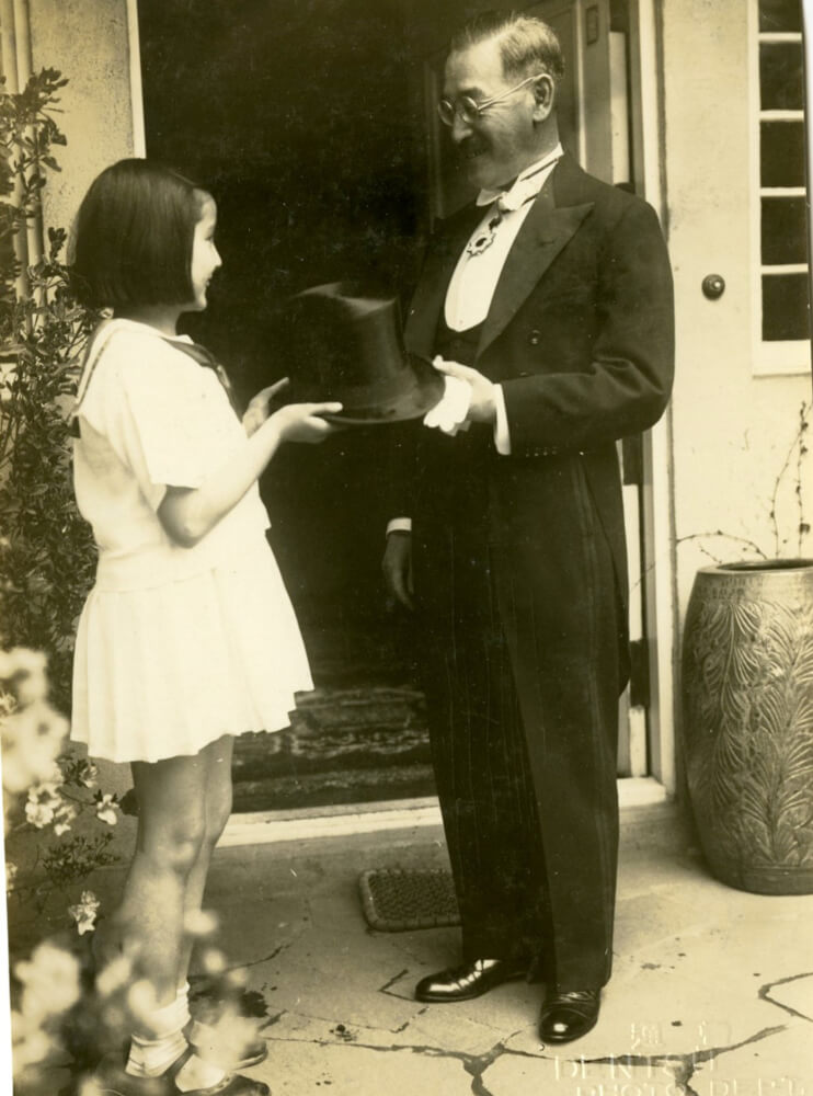 In a black and white image, Pia Kurusu White, left, hands her father Saburo Kurusu, right, his hat.