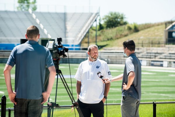 two media members interviewing head football coach Matt Mitchell