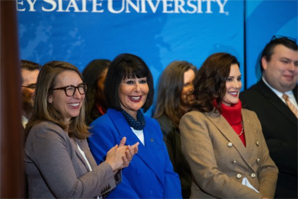 U.S. Rep. Hillary Scholten, Grand Valley President Philomena V. Mantella and Governor Gretchen Whitmer smile during a speaker's comments at the DeVos Center. 