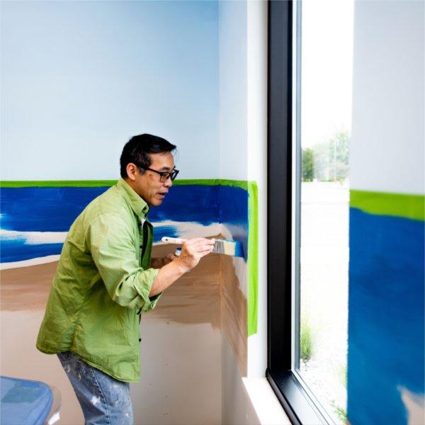 Paul Yu paints the wall at Little Red Dentistry