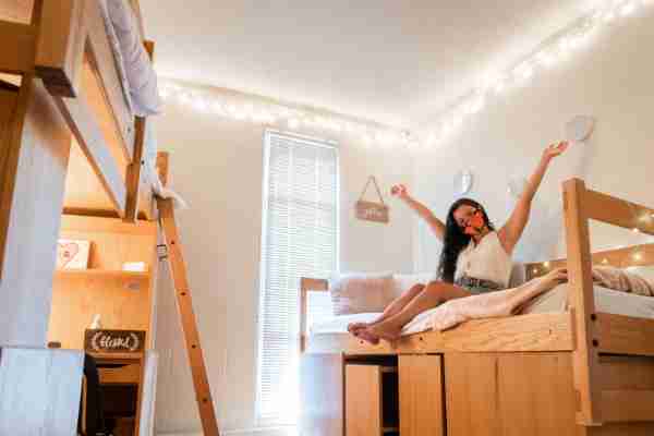 A student poses on her bed during GVSU move-in 2020. (Photo by Valerie Wojciechowski)