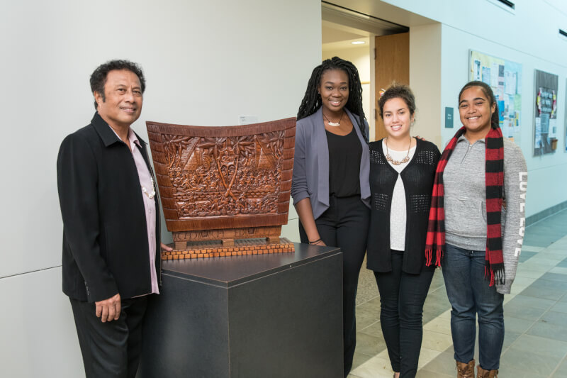 President Tommy Remengesau and students from Palau pose next to a traditional woodcarving from the country.