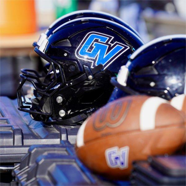Grand Valley football helmets and a football sit on a piece of equipment along the Lakers sideline.