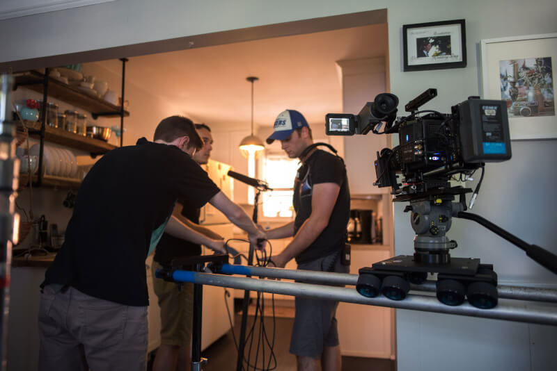 Sound utility Blaine Brown (front) and boom operator Keegan Cox (back right) working with 1st A.D. James Sturtridge (back left) to place a microphone and prepare a Dana Dolly track during the filming of "For the Birds."