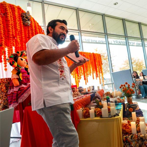 Rolando Mancera speaks in front of the Ofrenda at GVSU's D&#237;a de los Muertos celebration